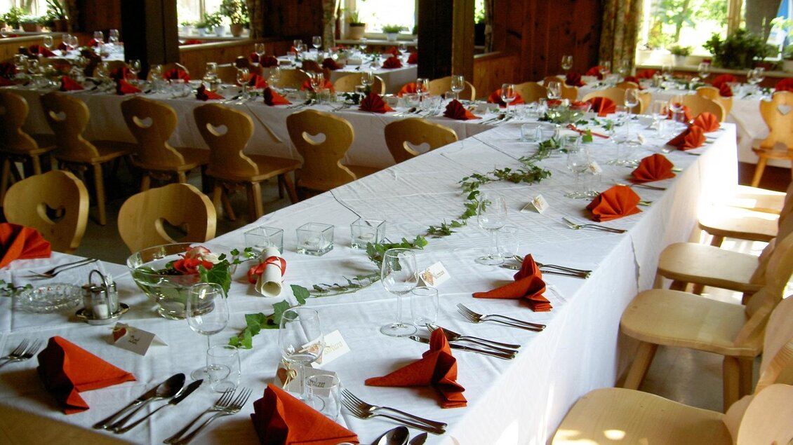 Ein festlich gedeckter Tisch mit roten Servietten und eleganten Gläsern. Im Hintergrund sind weitere Tische in einem hellen Raum zu sehen. | © Steinegger