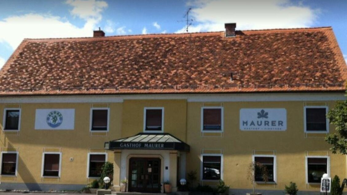 Ein Restaurantgebäude mit gelber Fassade und einem roten Ziegeldach. Es gibt zwei Schilder, eines mit einem Logo und das andere mit dem Namen „Maurer“. | © Tourismusverband Oststeiermark