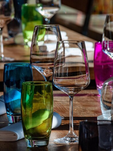 Colorful glasses are displayed on a wooden table. | © Pixabay
