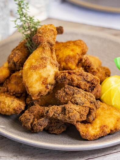 A plate with crispy, fried chicken and sides. A small lemon slice is decorated on the side. | © Graz Tourismus - Werner Krug