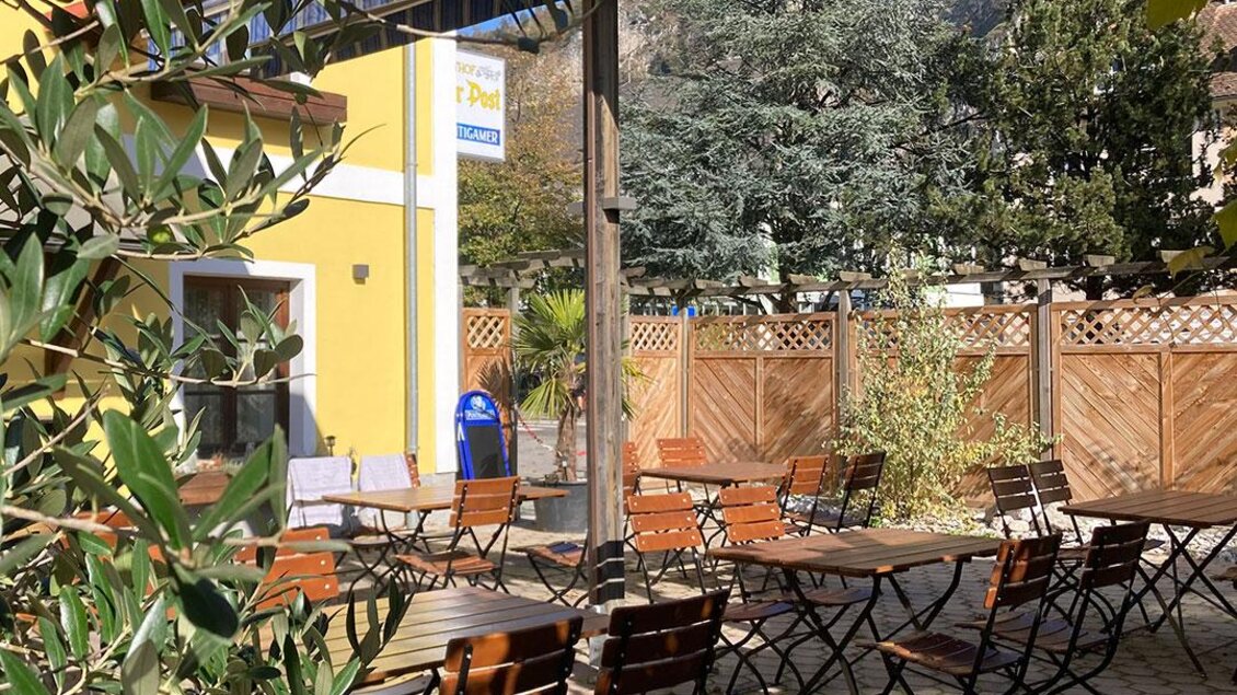 Gastgarten des Gasthofs Zur Post in Peggau mit Holztischen und Stühlen, umgeben von Pflanzen und Pergola. | © Gasthof Zur Post