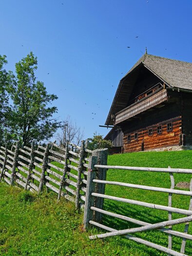 An old farmhouse with a fence and green meadow can be seen. | © Maria Fank