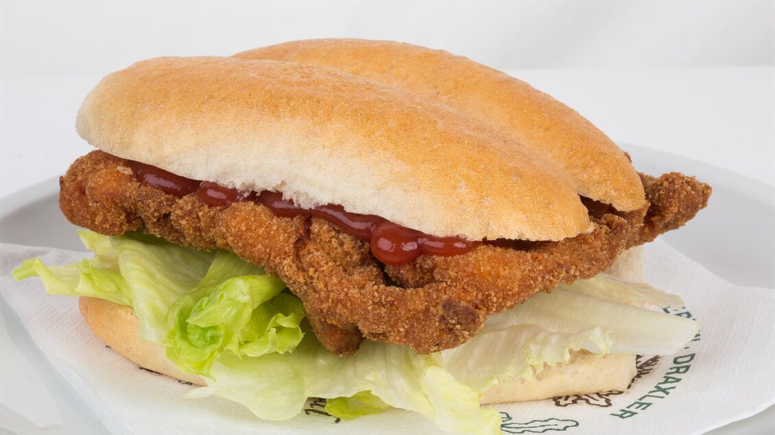 Semmerl mit knusprigem Hendl-Schnitzel, Blattsalat und Ketchup auf weißem Teller von Geflügel Draxler in Mooskirchen. | © Draxler