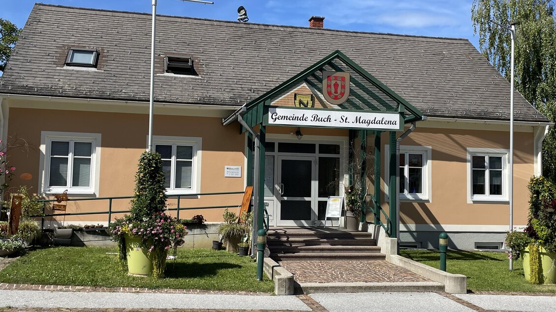 Das Bild zeigt ein gepflegtes Gemeindehaus mit einer einladenden Eingangstreppe. Vor dem Gebäude stehen grüne Pflanzen in Töpfen. | © Gemeinde Buch-St. Magdalena