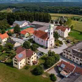 Eine malerische Dorfansicht mit einer Kirche im Zentrum. Umgeben von grünen Feldern und charmanten Häusern. | © Gemeinde Buch-St. Magdalena