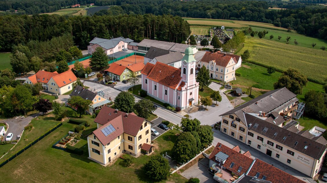 Eine malerische Dorfansicht mit einer Kirche im Zentrum. Umgeben von grünen Feldern und charmanten Häusern. | © Gemeinde Buch-St. Magdalena