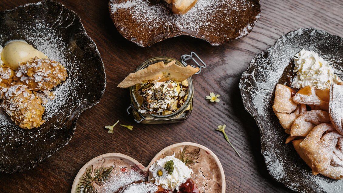 Ein schönes Arrangement von Desserts auf rustikalem Geschirr. Die verschiedenen Leckereien sind mit Puderzucker bestäubt und gut dekoriert. | © Genuss-Geschwister Kästenburg