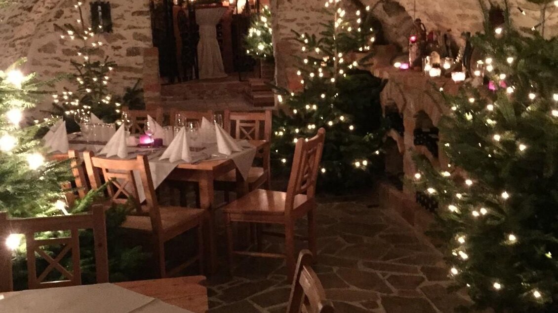 Ein gemütlicher Innenraum mit Holztischen und -stühlen. Der Raum ist festlich mit Weihnachtsbäumen und Lichtern dekoriert. | © Tourismusverband Oststeiermark