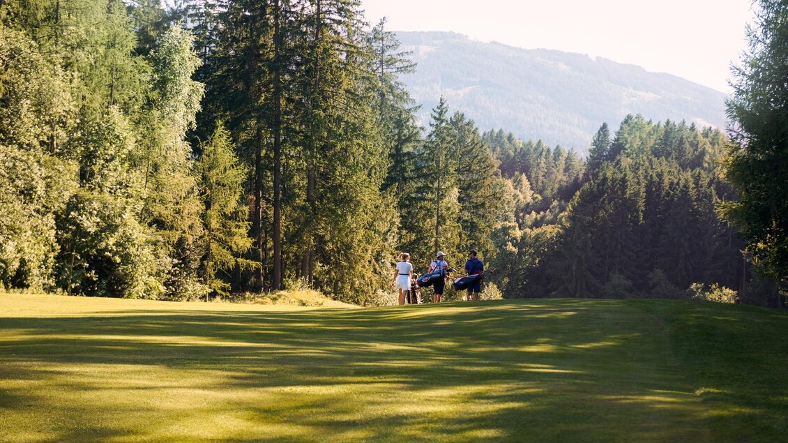 Eine malerische Golfplatzlandschaft mit gepflegtem Grün und hohen Bäumen. Im Hintergrund sind sanfte Hügel zu sehen. | © Edy Gröger