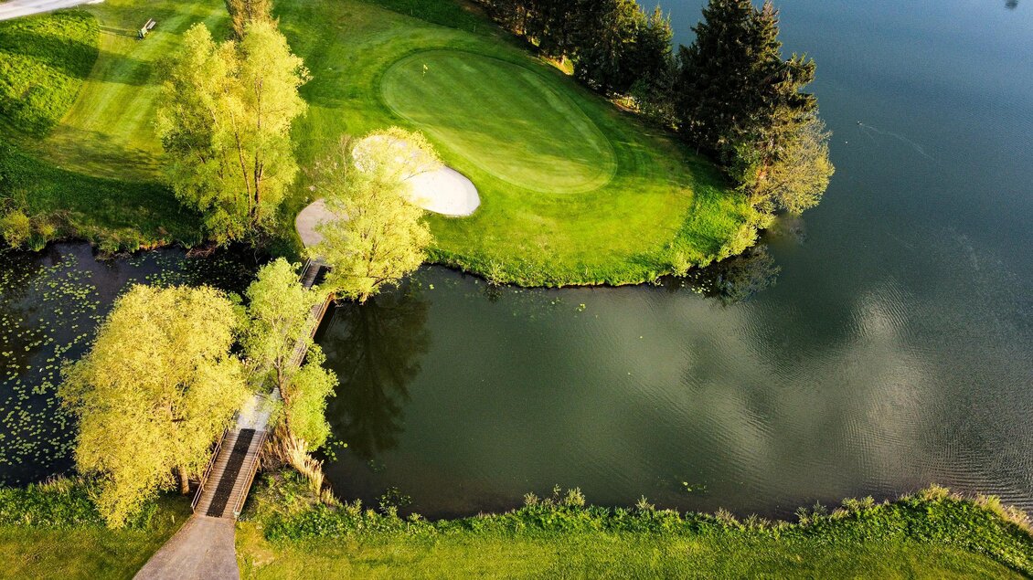 Luftaufnahme eines Greens mit Sandbunker direkt an einem See im Golfclub Erzherzog Johann in Maria Lankowitz. | © Golferlebnis Steiermark - Manuel Wiedner