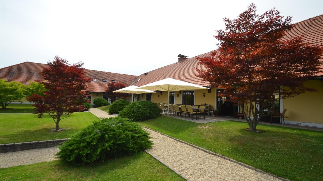 Ein schöner Garten mit gepflegtem Rasen und mehreren kleinen Bäumen. Im Hintergrund sieht man ein Gebäude mit einer überdachten Terrasse. | © GV Murstätten