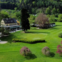 Luftaufnahme des Clubhauses und der gepflegten Golfanlage des Golfclubs Murhof mit blühenden Bäumen in Frohnleiten.  | © Golferlebnis Steiermark - Manuel Wiedner