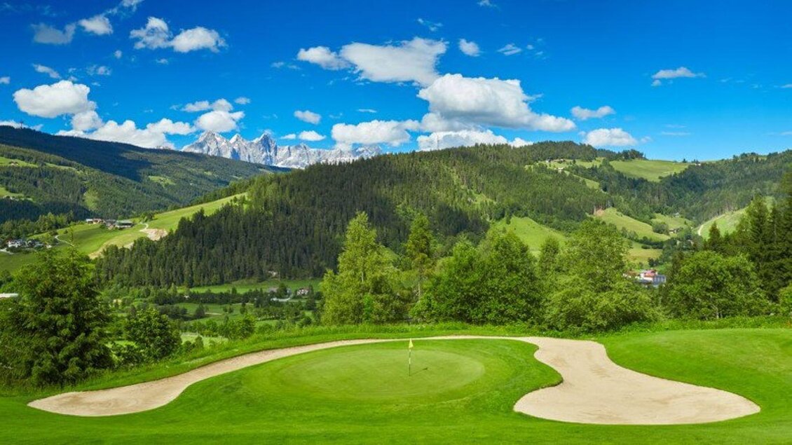 Eine malerische Golfplatzlandschaft mit sanften Hügeln und bewaldeten Bergen im Hintergrund. Der Himmel ist klar und blau, mit einigen weißen Wolken. | © Golfclub Radstadt