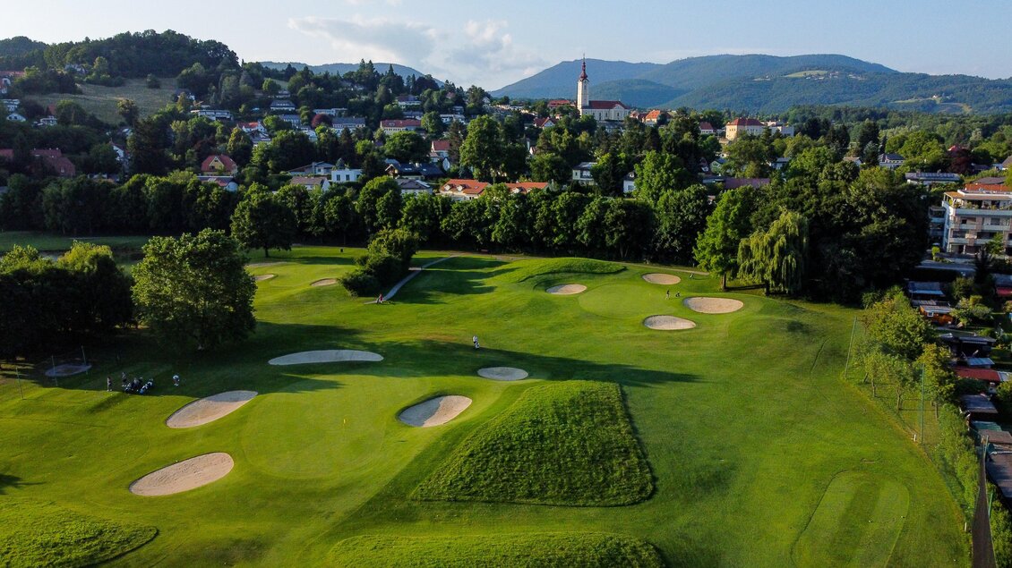 Luftaufnahme des Golfclubs Andritz mit Fairways, Sandbunkern und Ortskulisse im Hintergrund in Graz.  | © Golferlebnis Steiermark - Manuel Wiedner