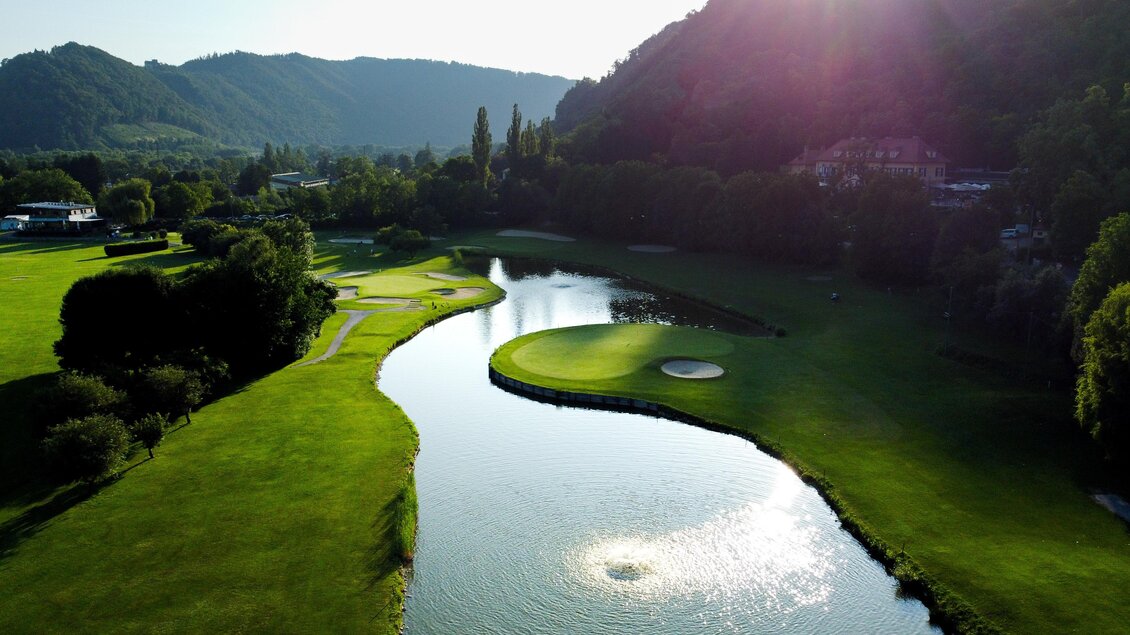 Luftaufnahme eines Inselgrüns mit Sandbunker und Wasserhindernis vor bewaldeten Hügeln im Golfclub Andritz in Graz.  | © Golferlebnis Steiermark - Manuel Wiedner