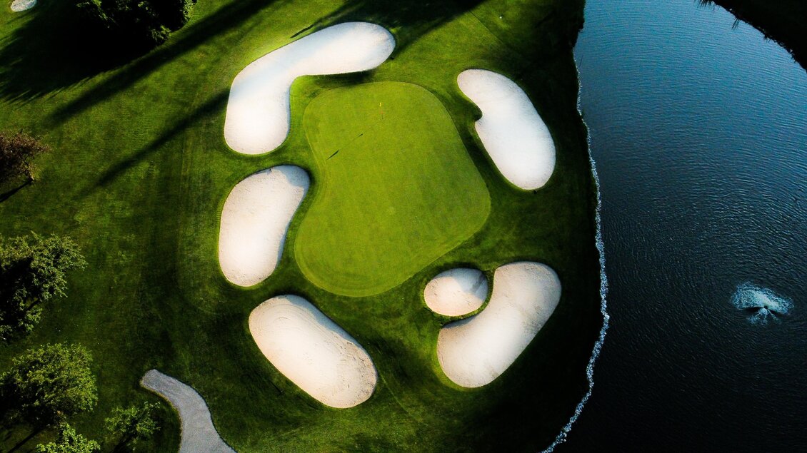 Senkrechte Luftaufnahme des Inselgrüns mit fünf Sandbunkern und Wasserhindernis im Golfclub Andritz in Graz. | © Golferlebnis Steiermark - Manuel Wiedner