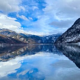 <p>Der ruhige Grundlsee in Richtung Gößl, umgeben von den schneebedeckten Ausläufern des Toten Gebirges im Ausseerland Salzkammergut. Der Himmel ist teilweise bewölkt und reflektiert sanft am zugefrorenen Grundlsee.</p> | © Bettina Scheck