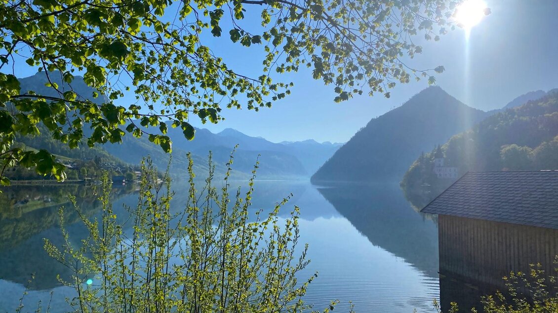 Der ruhige Grundlsee im Ausseerland Salzkammergut umgeben von Bergen und Bäumen an einem traumhaften Sommertag. Die Sonne scheint hell am klaren blauen Himmel. | © Bettina Scheck