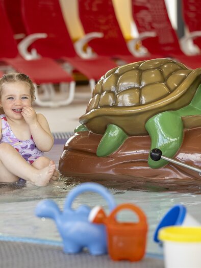 Ein Kind und eine Erwachsene verbringen Zeit im Wasser. Neben ihnen steht ein buntes, aufblasbares Schildkröten-Spielzeug. | © H2O-Hoteltherme GmbH