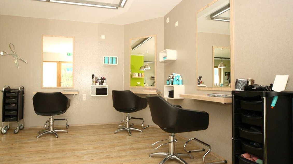 Ein moderner Friseursalon mit stilvollen Stühlen und Spiegeln. Die Wände sind hell und die Einrichtung ist schlicht und elegant. | © Haarschnitt
