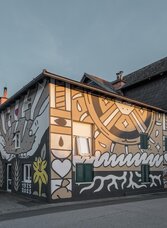 Painted facade of the Haindl Mill in Kalsdorf near Graz with a water wheel and symbols | © ee photograph - Elena Egger