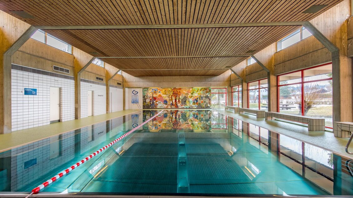 Ein helles Schwimmbad mit klaren Wasser und Holzdecke. Die Wände sind mit bunten Bildern dekoriert. | © Stadtgemeinde Trofaiach