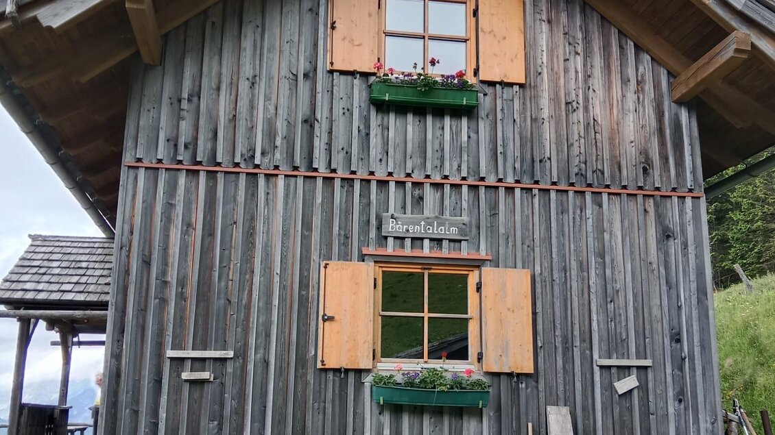 Ein traditionelles Holzhaus mit Holzläden und Fensterkästen. Es ist von einer grünen Wiese umgeben. | © Rinnhofer