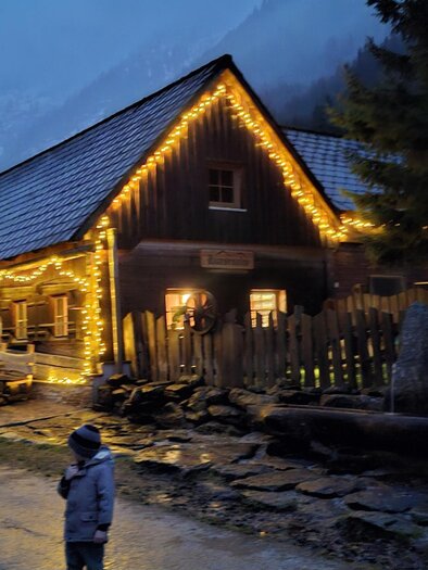 Ein gemütliches Holzhaus, das sanft beleuchtet ist. Es ist Abenddämmerung und die Umgebung wirkt malerisch und einladend. | © Martin Heller