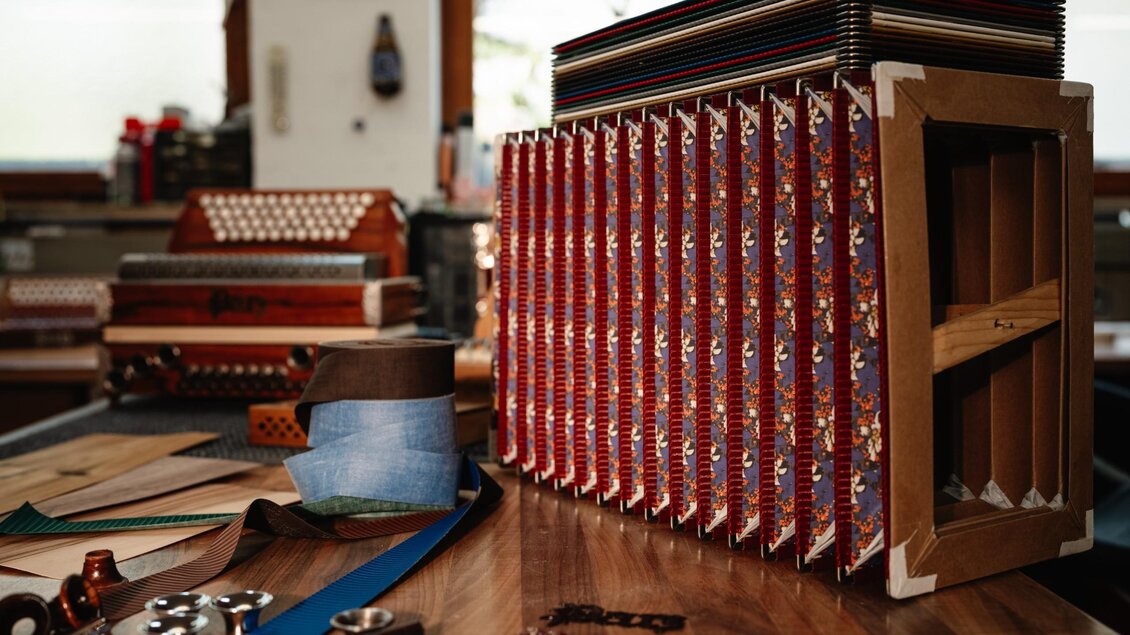 Gemusterte Bälge für Steirische Harmonikas liegen zur Verarbeitung auf einer Werkbank. | © Bernd Grosseck