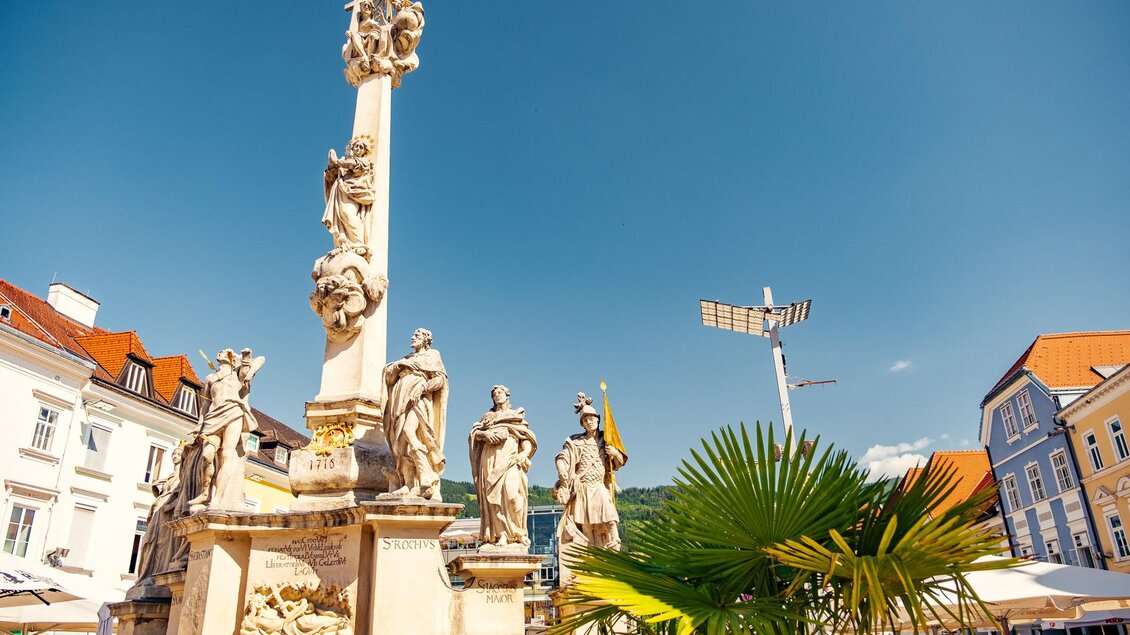 Ein schöner Platz mit einer beeindruckenden Säule und mehreren Statue von Heiligen. Der klare blaue Himmel und die umliegenden Gebäude verleihen der Szene ein einladendes Ambiente. | © TVB Erzberg-Leoben