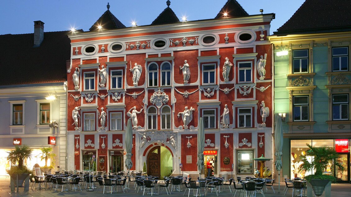 Eine malerische Stadtansicht mit roten Dächern und grünen Hügeln im Hintergrund. Die Architektur zeigt eine Mischung aus historischen und modernen Gebäuden. | © TVB Erzberg-Leoben