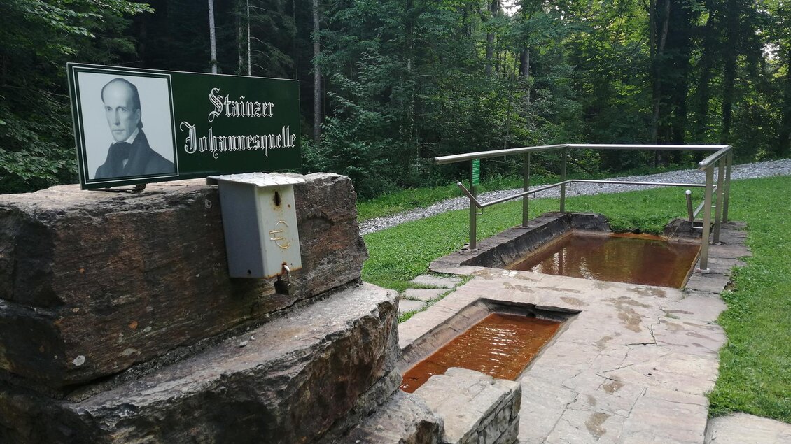 Eine Quelle im Wald mit einem Steinsockel. Neben der Quelle steht ein Schild mit dem Namen "Johannesquelle". | © TV Südsteiermark