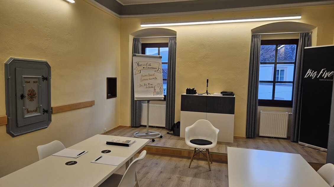Ein moderner Besprechungsraum mit einem großen Tisch, Stühlen und einem Flipchart. Die Wände sind hell gestrichen und es gibt große Fenster, die natürliches Licht hereinlassen. | © Dekkers