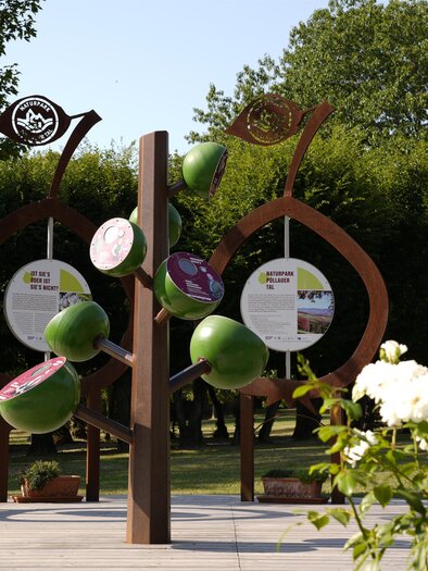 Ein moderner Skulpturenpark mit mehreren großen, organisch geformten Stelen. Eingerahmt von weißen Rosenblüten und grünen Bäumen. | © Tourismusverband Oststeiermark