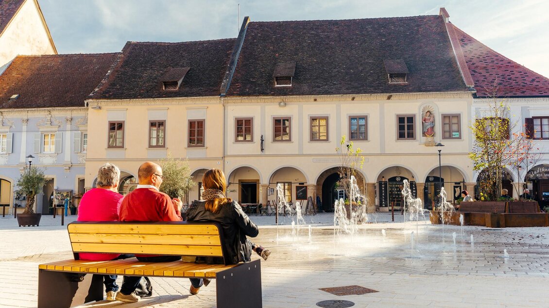 Hauptplatz von Bad Radkersburg mit Wasserspielen, Sitzbank und historischen Häusern mit Arkaden in der Altstadt. | © Zehnerhaus Bad Radkersburg