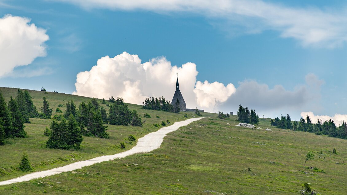 Zu sehen ist eine Schotterstraße auf den Gipfel des Hochwechsels mit leicht bewölkten Himmel. | © Kurt Elmleitner