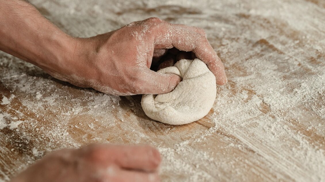 Eine bemehlte Hand formt eine Semmel auf der Arbeitsfläche der Hofbäckerei Edegger-Tax. | © Bernd Grosseck