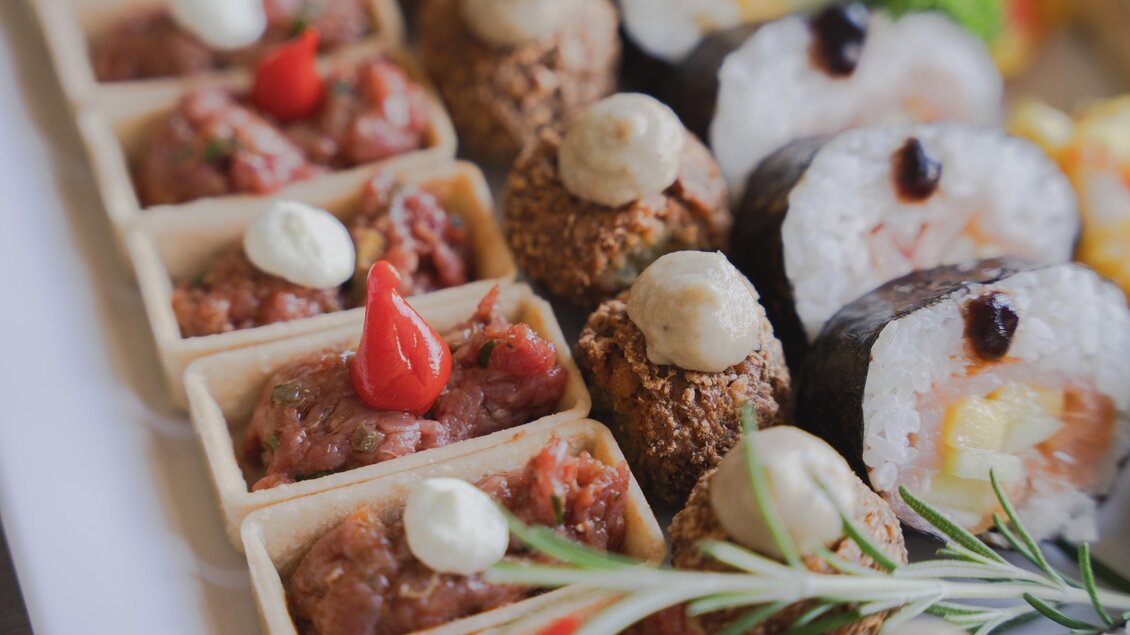 Eine Auswahl an köstlichen Häppchen, darunter Beef Tatar in kleinen Körbchen, gefüllte Fleischbällchen und Sushi, dekoriert mit frischen Kräutern und Saucen in der Hofkuchl in Semriach.  | © Wolfgang Hummer
