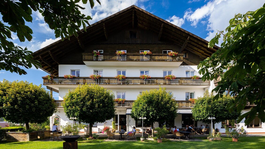 Blick auf den Semriacherhof im Sommer, umgeben von einem Garten mit grünen Bäumen und bunten Blumen. Der sonnige Himmel und die einladende Atmosphäre schaffen einen charmanten Eindruck in Semriach. | © TV Region Graz - Harry Schiffer