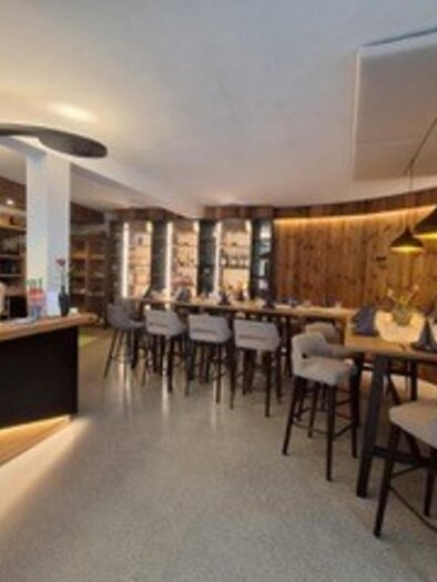 A modern bar with wood decor and comfortable seating. Bright lighting creates an inviting atmosphere. | © Fam. Garber