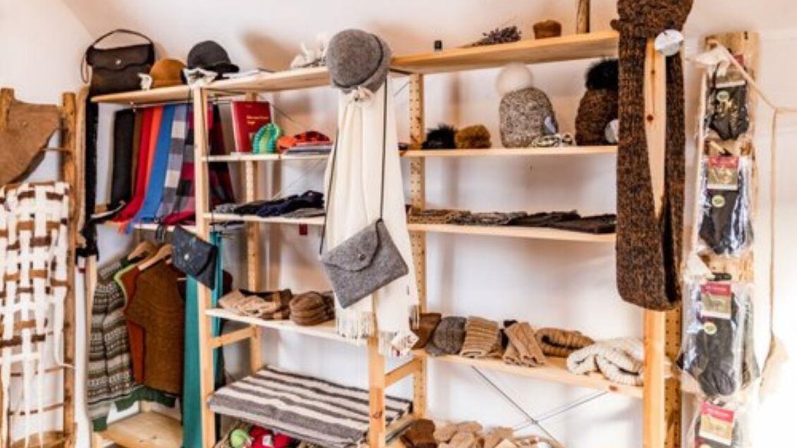 Ein gemütlicher Verkaufsraum mit Regalen, die handgemachte, gestrickte Waren wie Mützen, Schals und Decken zeigen. Die Wände sind hell, und die Atmosphäre ist einladend. | © Klausernhof