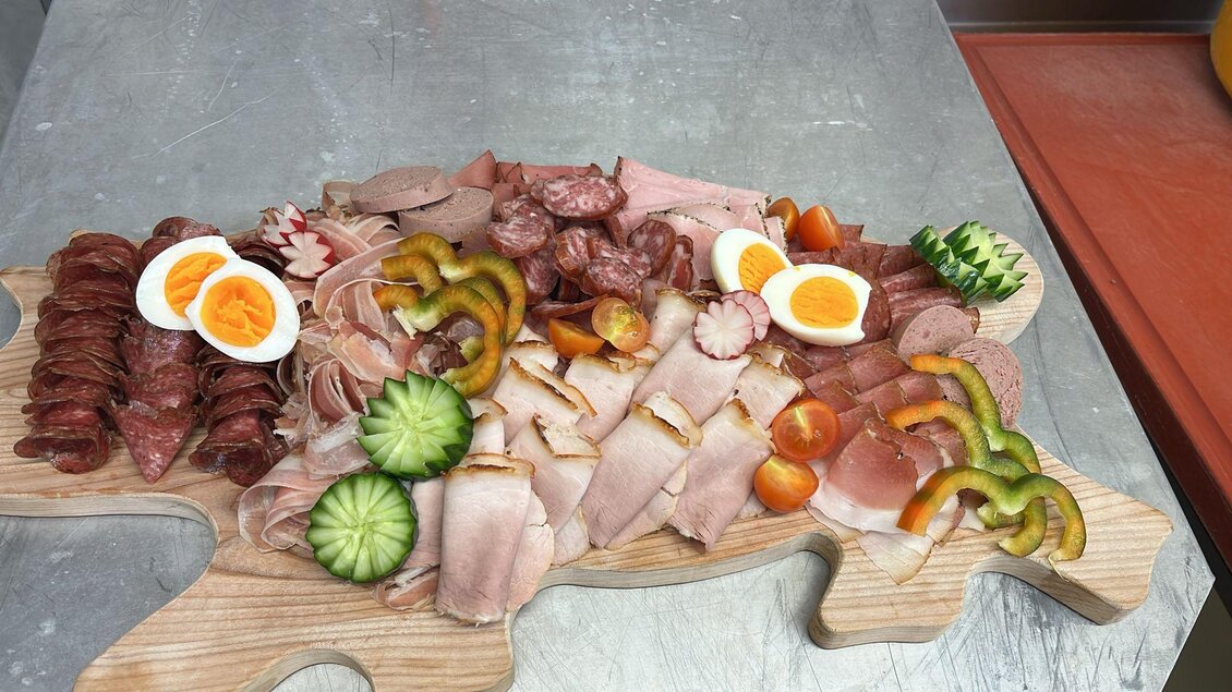 Ein reichhaltiges Wurst- und Käsebrett auf einem Holzbrett, dekoriert mit frischem Gemüse und Eiern. Die Präsentation ist ansprechend und vielfältig in der Auswahl. | © TV Murau