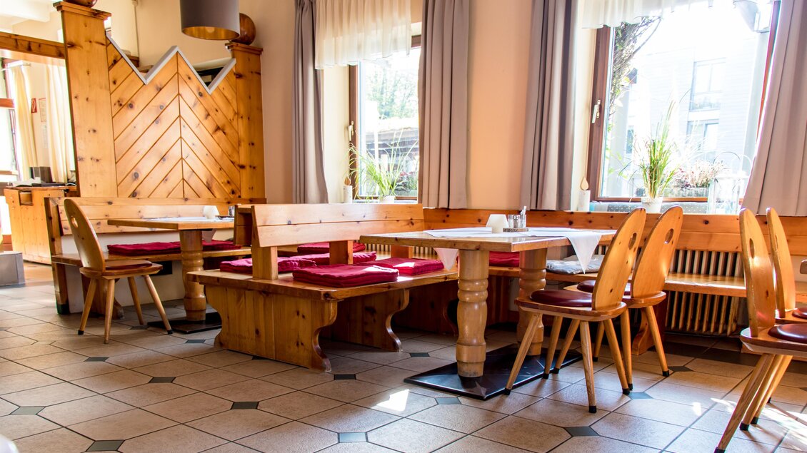 Ein gemütliches Restaurant mit Holzmobiliar und hellen Fenstern. Die Tische und Stühle sind ordentlich angeordnet und schaffen eine einladende Atmosphäre. | © Römerhof