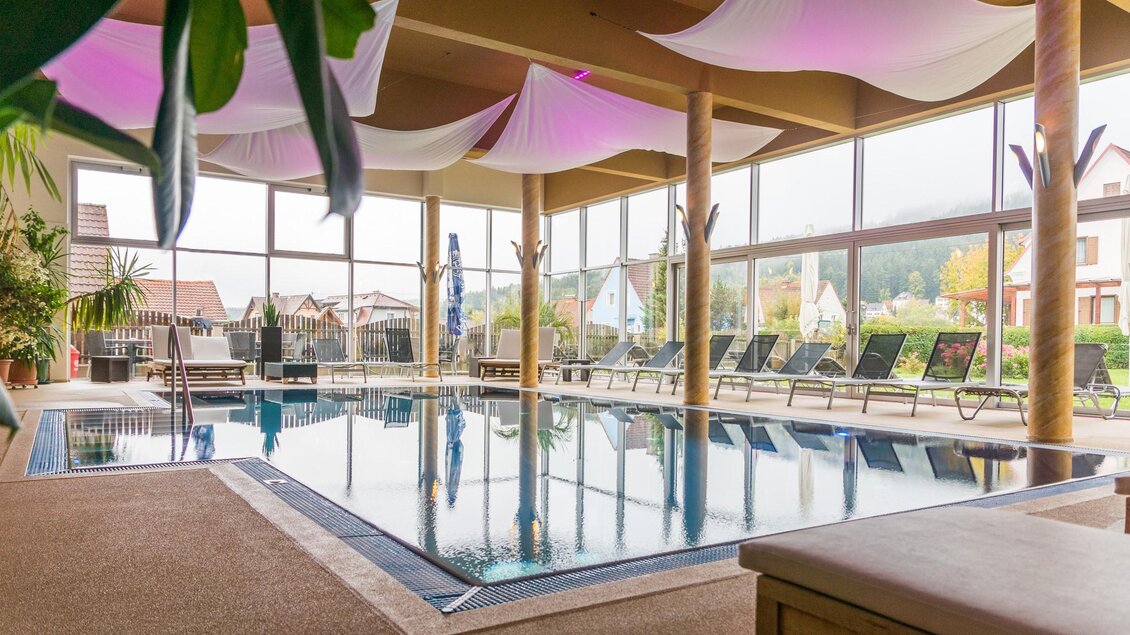 Ein eleganter Innenpool mit großen Fenstern und entspannender Atmosphäre. Umgeben von Liegen und Pflanzen vermittelt der Raum ein Gefühl von Luxus und Ruhe. | © Hotel Angerer-Hof
