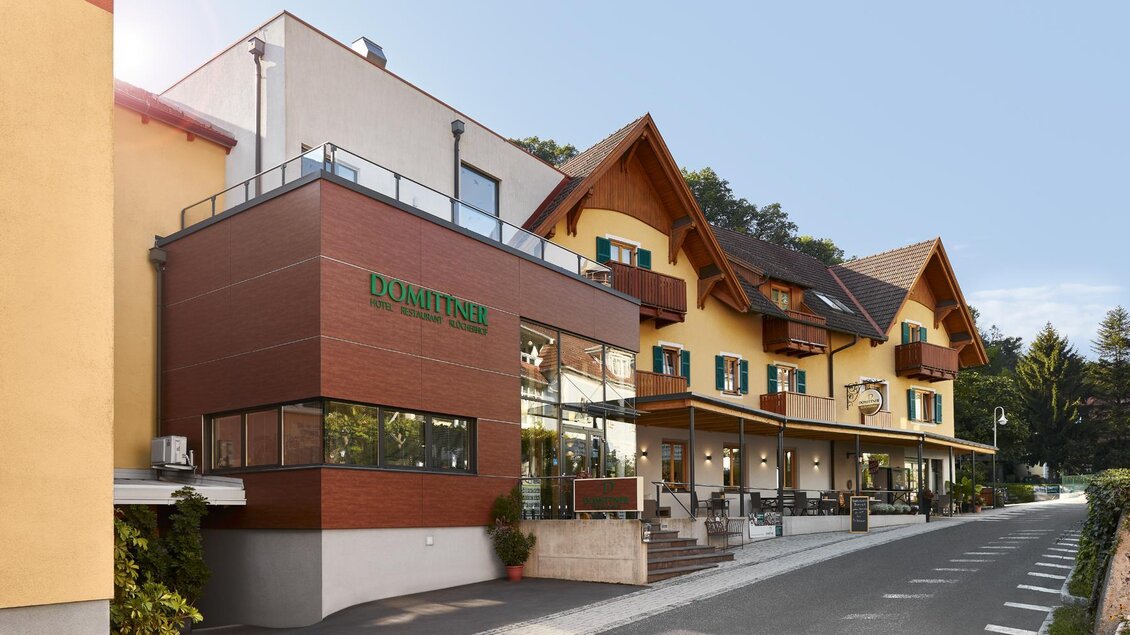 Ein modernes Hotelgebäude mit traditioneller Architektur. Die Fassade kombiniert Holz- und Stein-Elemente und ist von einer schönen Umgebung umgeben. | © Klöcherhof Domittner