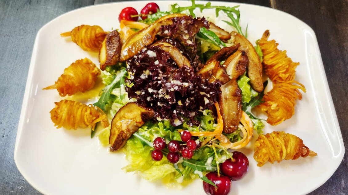 Ein dekorativer Salat mit gebackenen Garnelen, Pilzen, frischen Blattgemüsen und roten Beeren. Die speisen sind kunstvoll angerichtet und laden zum Verzehr ein.