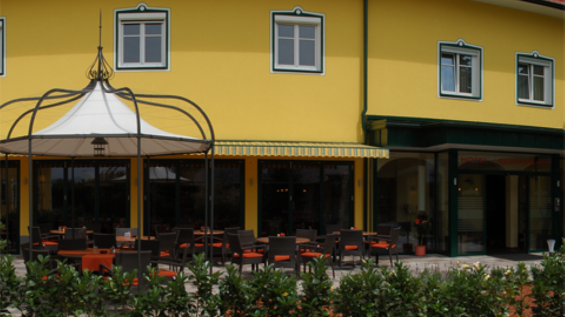 Ein gemütliches Restaurant mit einer gelben Fassade und einer einladenden Terrasse. Rund um die Terrasse sind grüne Pflanzen angeordnet. | © Hotel-Restaurant Neuhold