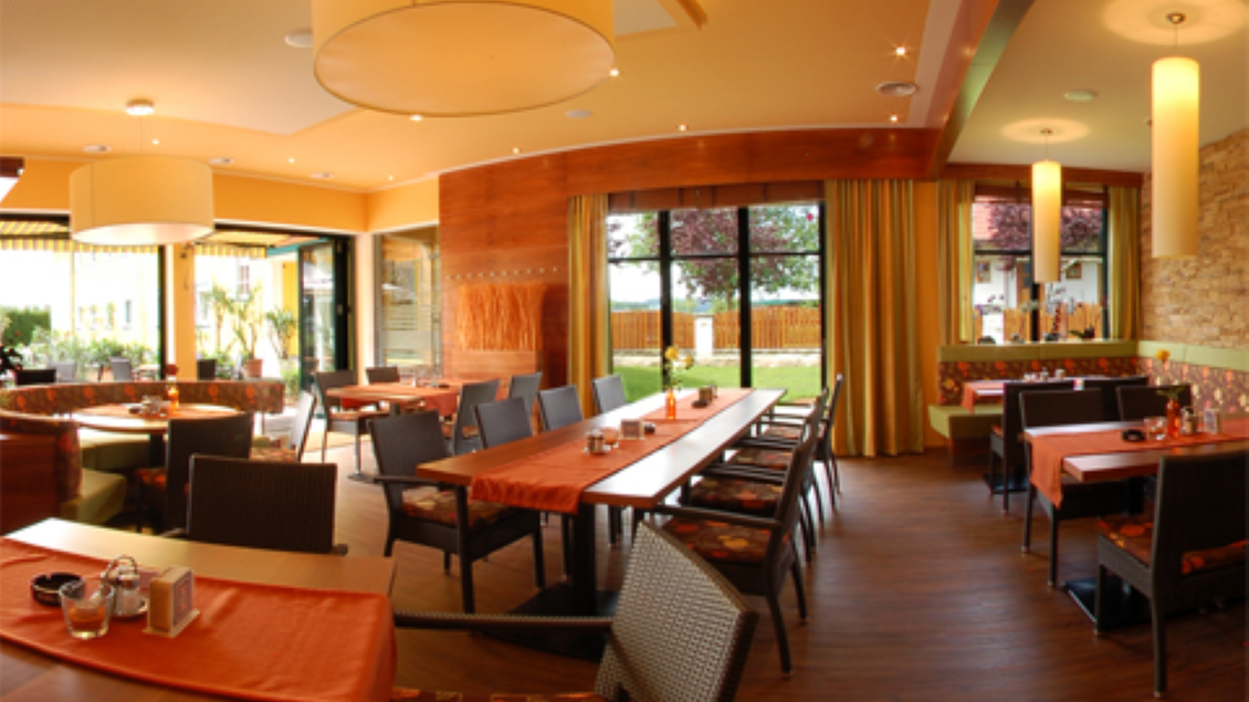 Ein gemütliches Restaurant mit Holztischen und Stühlen. Große Fenster lassen viel Licht herein und bieten Blick auf einen Garten. | © Hotel-Restaurant Neuhold