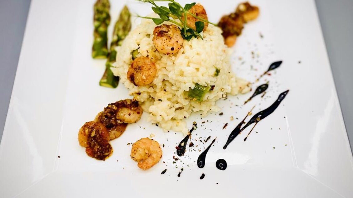 Ein leckerer Risotto mit Garnelen und Spargel auf einem weißen Teller. Die Präsentation ist elegant mit einer Balsamicoreduktion. | © Hotel-Restaurant Schwarzer Adler