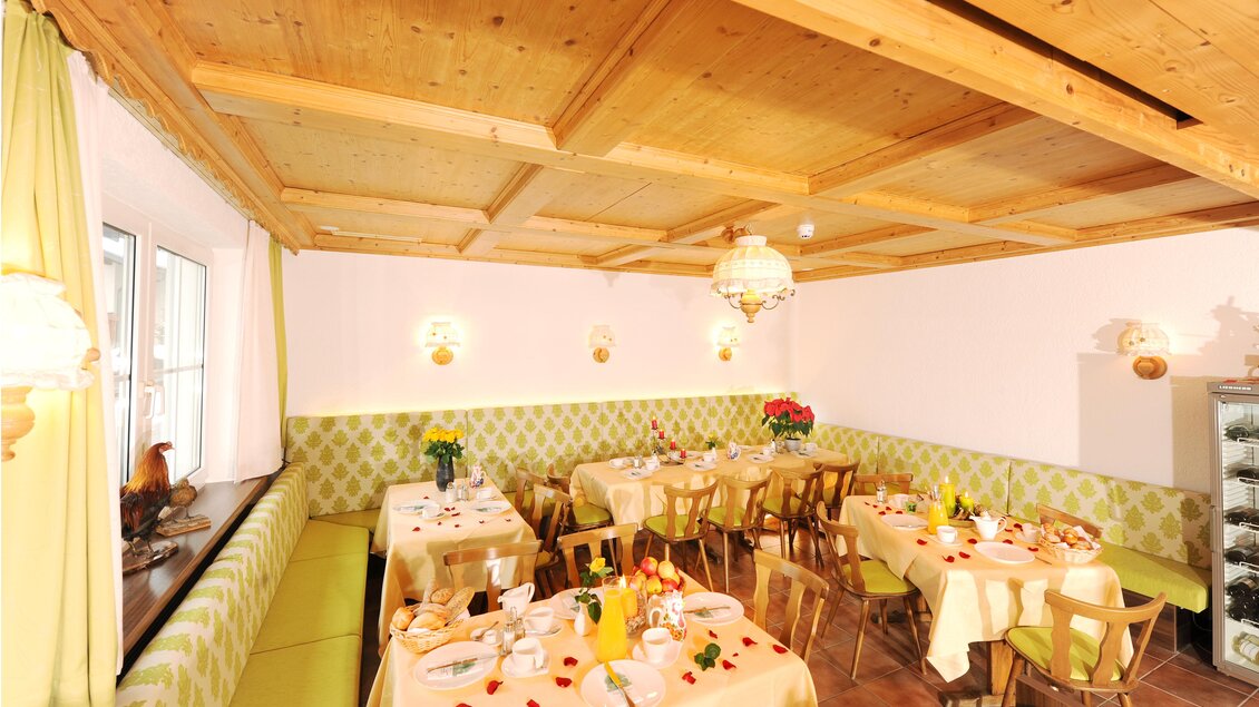 Ein gemütlicher Speiseraum mit Holzdecke und dekorativen Lampen. Die Tische sind gedeckt und mit frischen Blumen geschmückt. | © Hotel Seebacherhof/Hagspiel